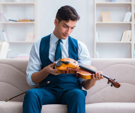 Young musician man practicing playing violin at homeの写真素材