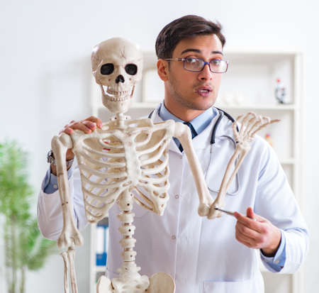 Yong male doctor with skeleton isolated on whiteの写真素材