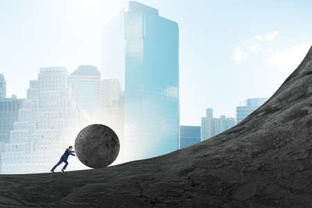 Man pushing large stone to the topの写真素材