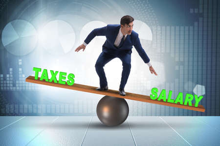 Businessman balancing between taxes and salaryの写真素材