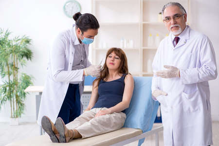 Two male doctors and young woman in plastic surgery conceptの写真素材