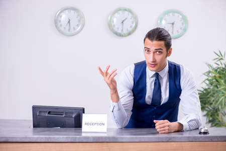 Young man receptionist at the hotel counterの写真素材
