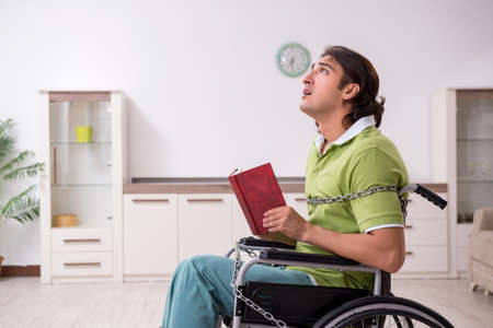 Young male invalid in wheel-chair suffering at homeの写真素材