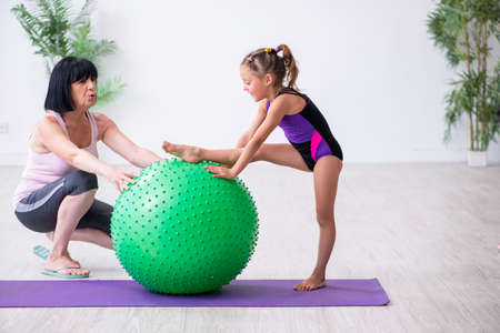 Girl and mother exercising at homeの写真素材