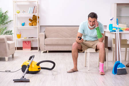 Young injured man cleaning the houseの写真素材