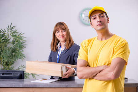 Young male courier delivering box to hotels reception
