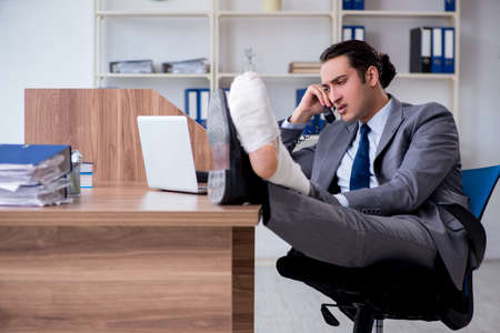 Leg injured male employee in the officeの写真素材
