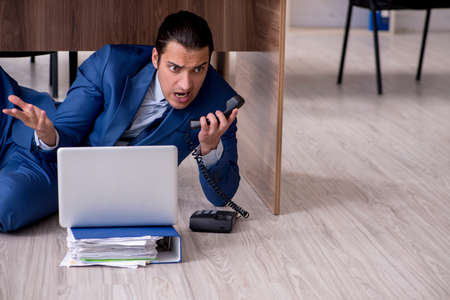 Young male employee and too many work in the officeの写真素材