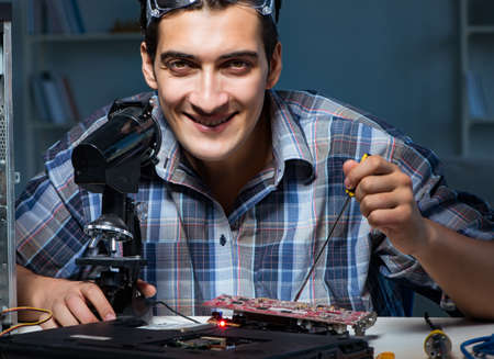 Repairman trying to repair laptop with miscroscopeの写真素材