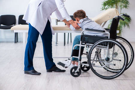 Young male doctor pediatrist and boy in wheel-chairの写真素材