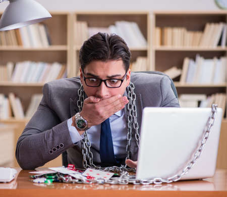 Young businessman addicted to online gambling cards playing in tの写真素材