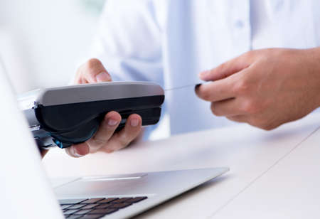 The man processing credit card transaction with pos terminalの写真素材