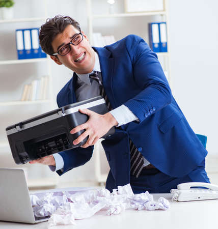 Businessman angry at copying machine jamming papersの写真素材