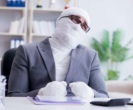 Bandaged businessman worker working in the office doing paperworの写真素材