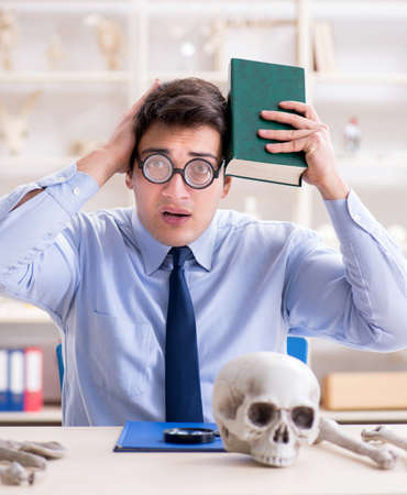 Funny crazy professor studying human skeletonの写真素材