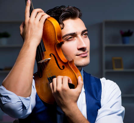 Young musician man practicing playing violin at homeの写真素材