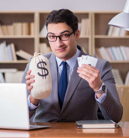 Businessman gambling playing cards at workの写真素材