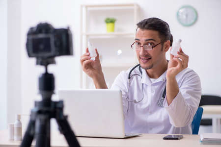 Young male doctor recording video for his blogの写真素材