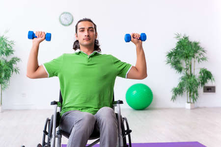 Young man in wheel-chair doing exercises indoorsの写真素材