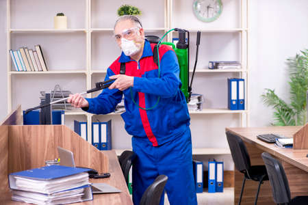 Old professional contractor doing pest control in the officeの写真素材