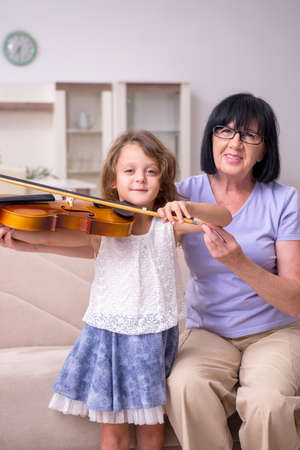 Old lady teaching little girl to play violinの写真素材