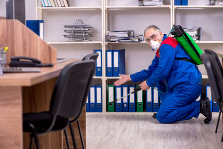 Old professional contractor doing pest control in the officeの写真素材