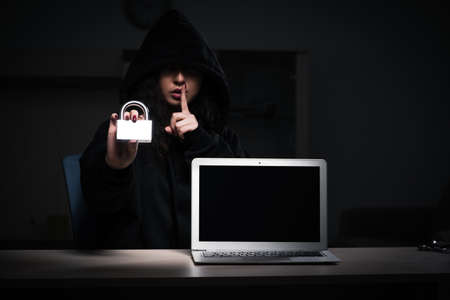 Female hacker hacking security firewall late in officeの写真素材