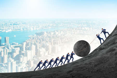 Teamwork example with business people pushing stone to topの写真素材