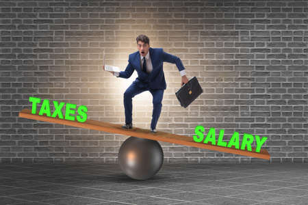 Businessman balancing between taxes and salaryの写真素材