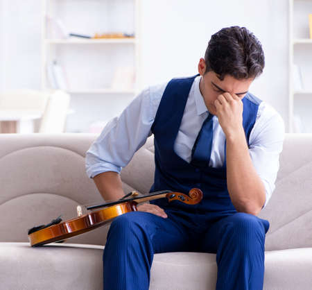 Young musician man practicing playing violin at homeの写真素材