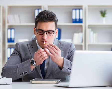 Businessman smoking in office at workの写真素材