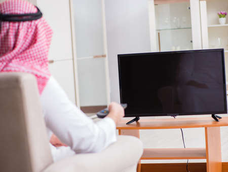 Arab businessman watching tv at home