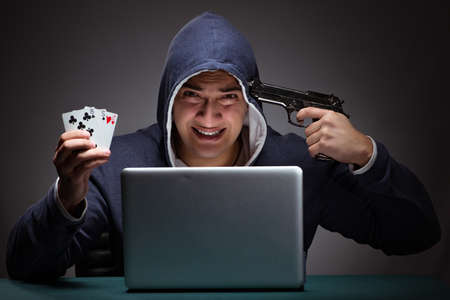 Young man wearing a hoodie sitting in front of a laptop computer