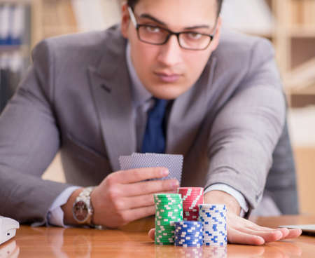 Businessman gambling playing cards at workの写真素材