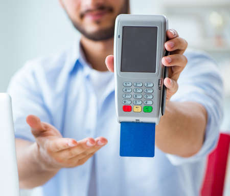 Man processing credit card transaction with POS terminalの写真素材