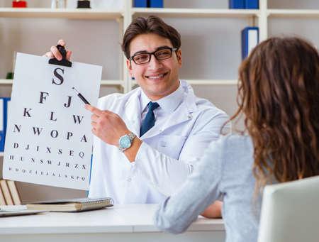 Doctor optician with letter chart conducting an eye test checkの写真素材