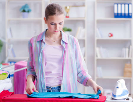 Happy housewife doing ironing at homeの写真素材