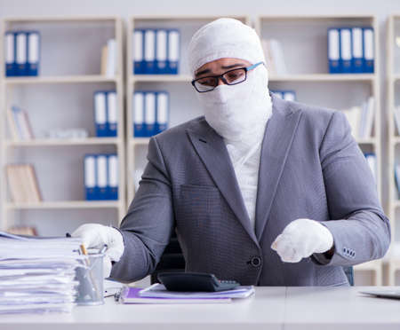 Bandaged businessman worker working in the office doing paperworの写真素材