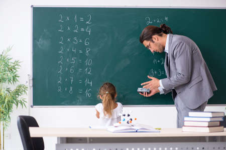 Teacher with young girl in the classroomの写真素材