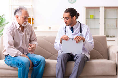 Young male doctor visiting old patient at homeの写真素材