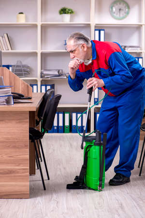 Old professional contractor doing pest control in the officeの写真素材