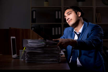 Young male employee working night in the officeの写真素材