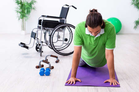Young man in wheel-chair doing exercises indoorsの写真素材