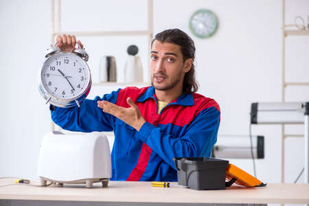 Young male contractor repairing toaster at workshopの写真素材