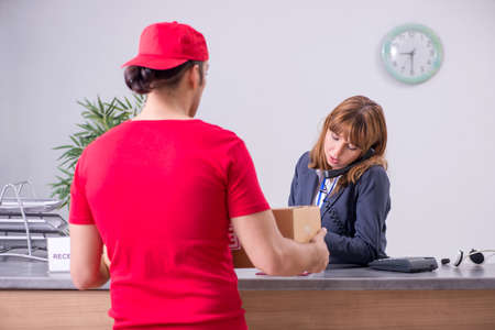 Young male courier delivering box to hotels reception