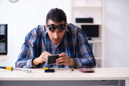 Young handsome technician repairing mobile phone