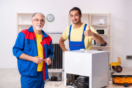 Two contractors repairing fridge at workshopの写真素材