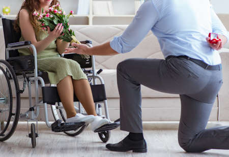 Man making marriage proposal to disabled woman on wheelchairの写真素材