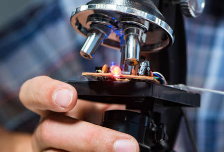 Repairman trying to repair laptop with miscroscope