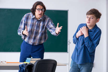 Funny male teacher and boy in the classroomの写真素材